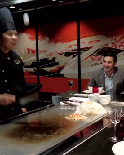 A chef cooking at a teppanyaki counter for seated guests on board