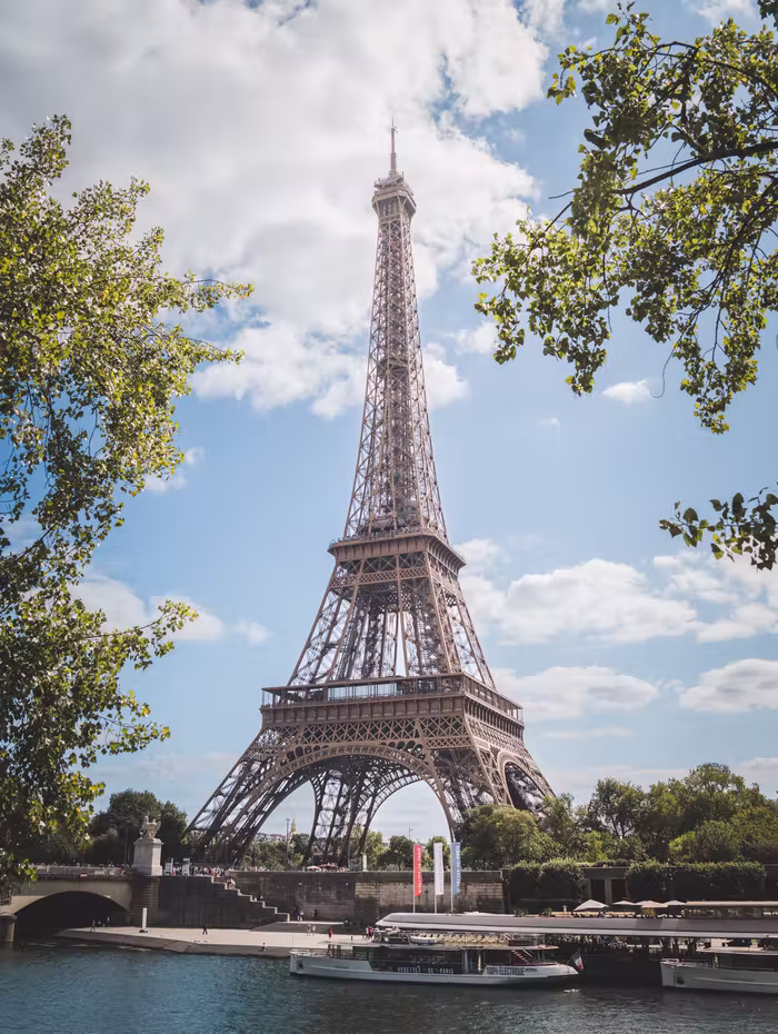 The Eiffel Tower framed by trees above the Seine