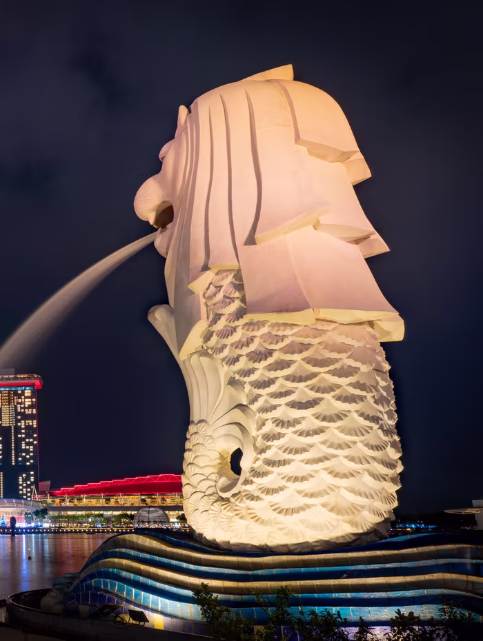 The Merlion lit at night with Marina Bay Sands behind