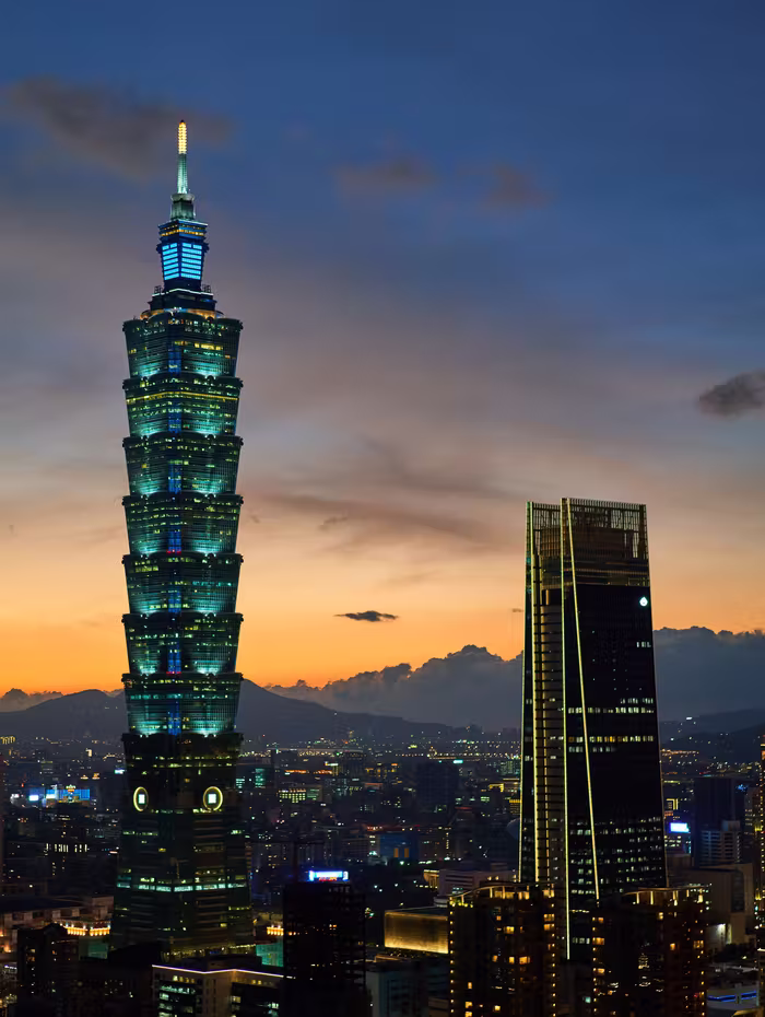 Taipei 101 lit at dusk above the city