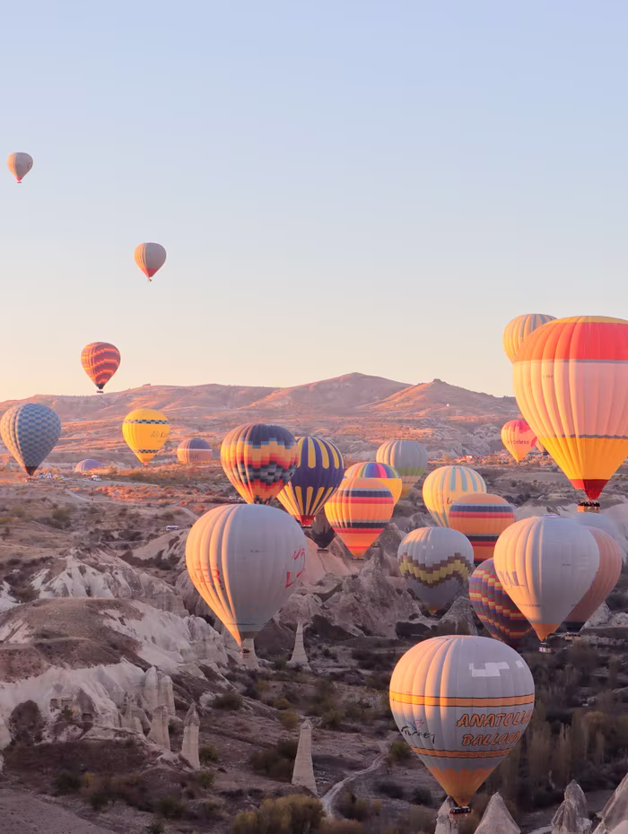 Hot-air balloons rising over the Cappadocia valleys at dawn
